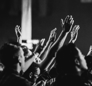 grayscale photo of people raising their hands